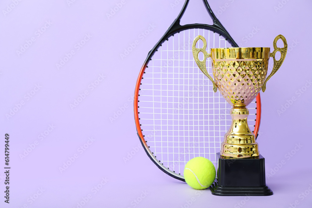 Gold cup with tennis racket and ball on lilac background