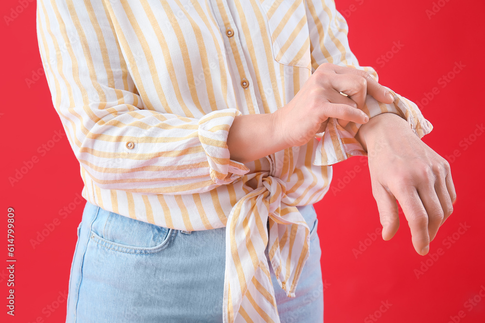 Mature woman rolling up her sleeve on red background, closeup