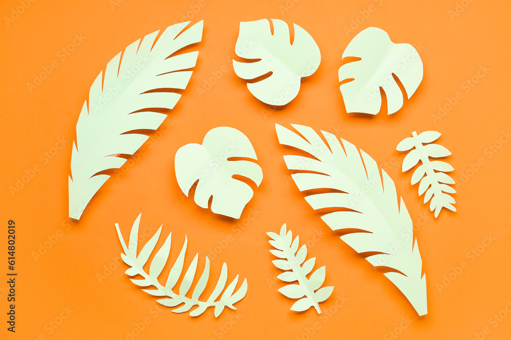 Light paper tropical leaves on orange background