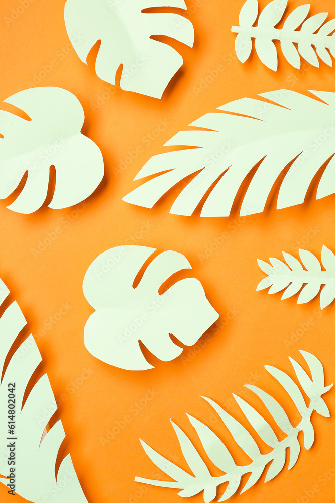 Light paper tropical leaves on orange background