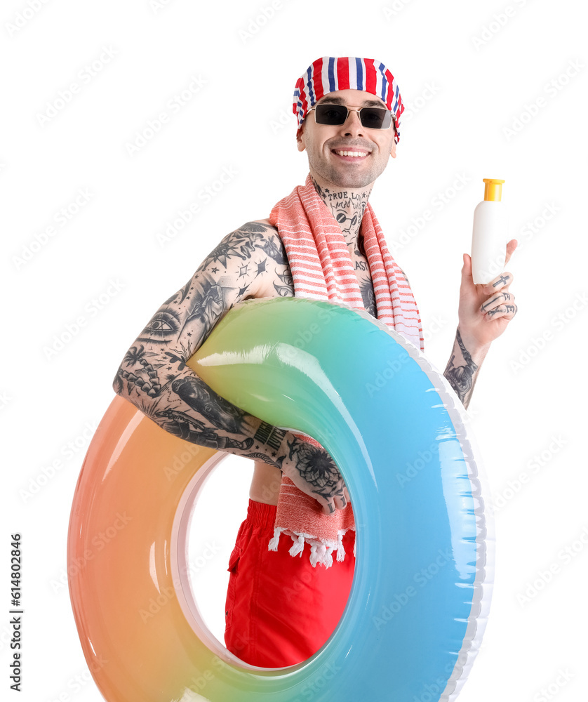 Tattooed man with sunscreen cream and swimming ring on white background