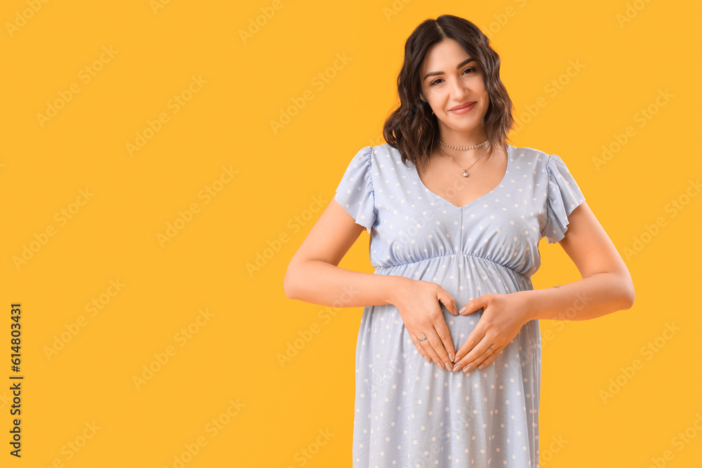 Young pregnant woman on yellow background