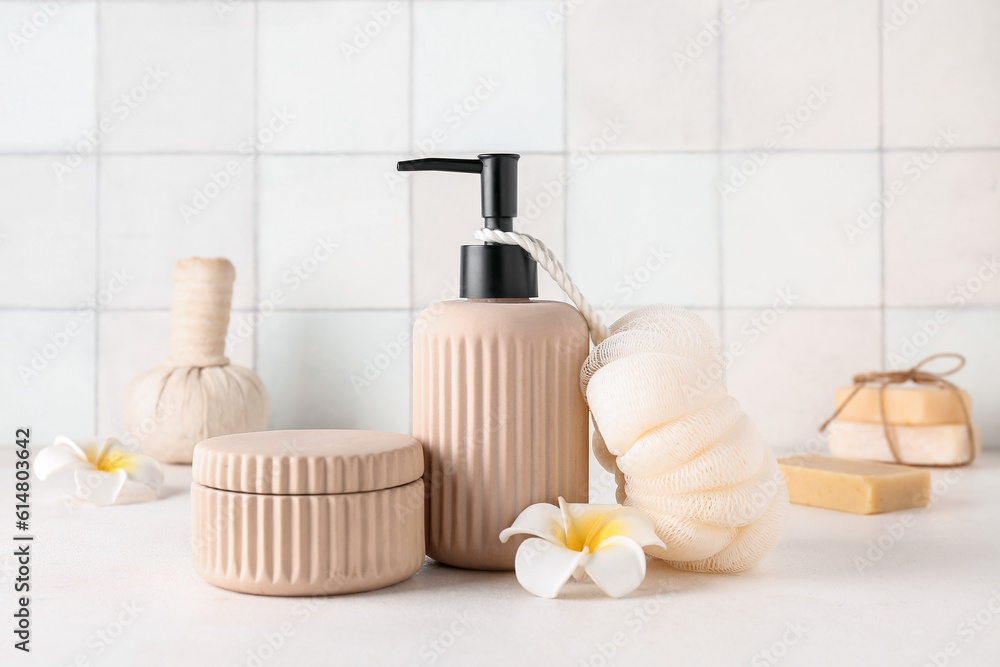 Spa composition with soap dispenser, washcloth and plumeria flowers on white table