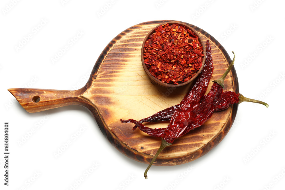 Board with dry hot chili with bowl of ground pepper on white background