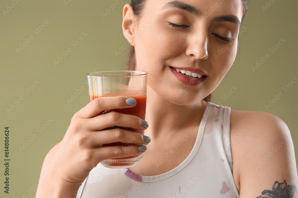 Sporty young woman with glass of vegetable juice on green background, closeup