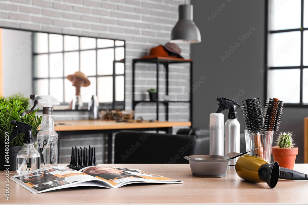 Different hairdressing tools and magazine on table in beauty salon