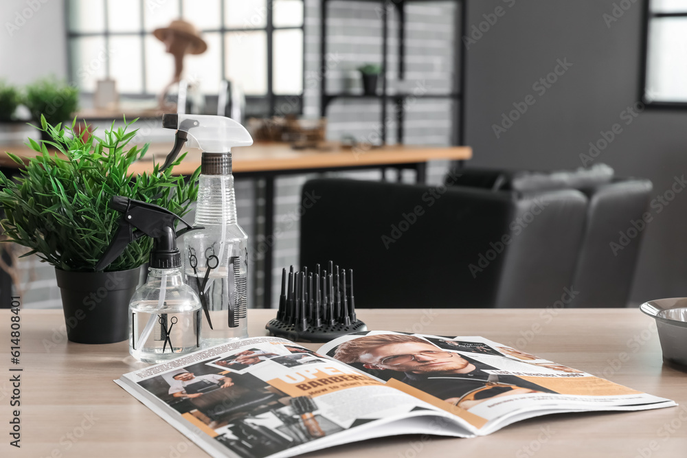 Hairdressing tools and magazine on table in beauty salon