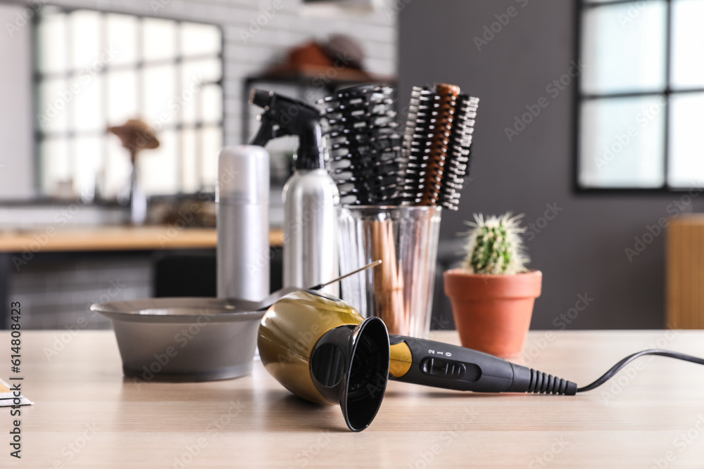 Modern hair dryer on table in beauty salon