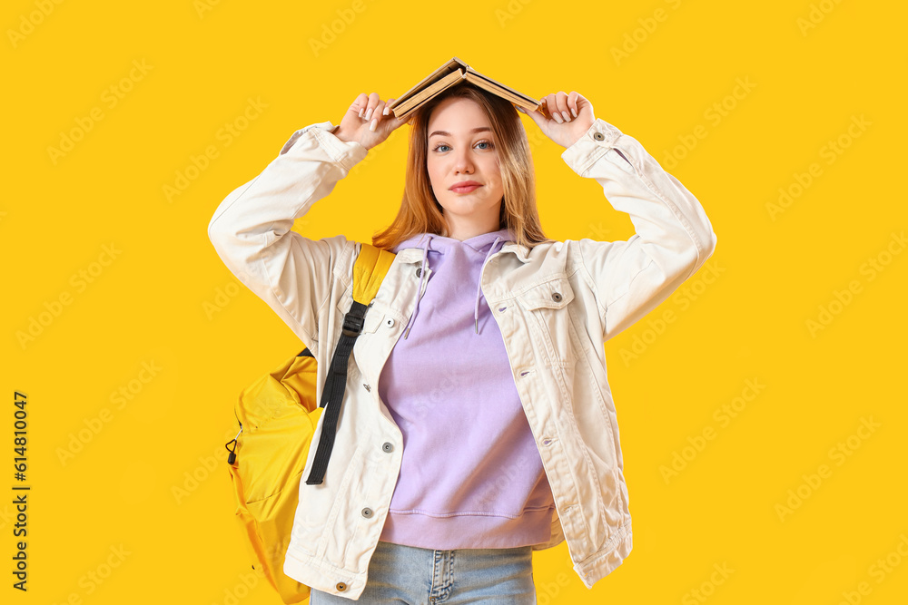 Female student with book on yellow background