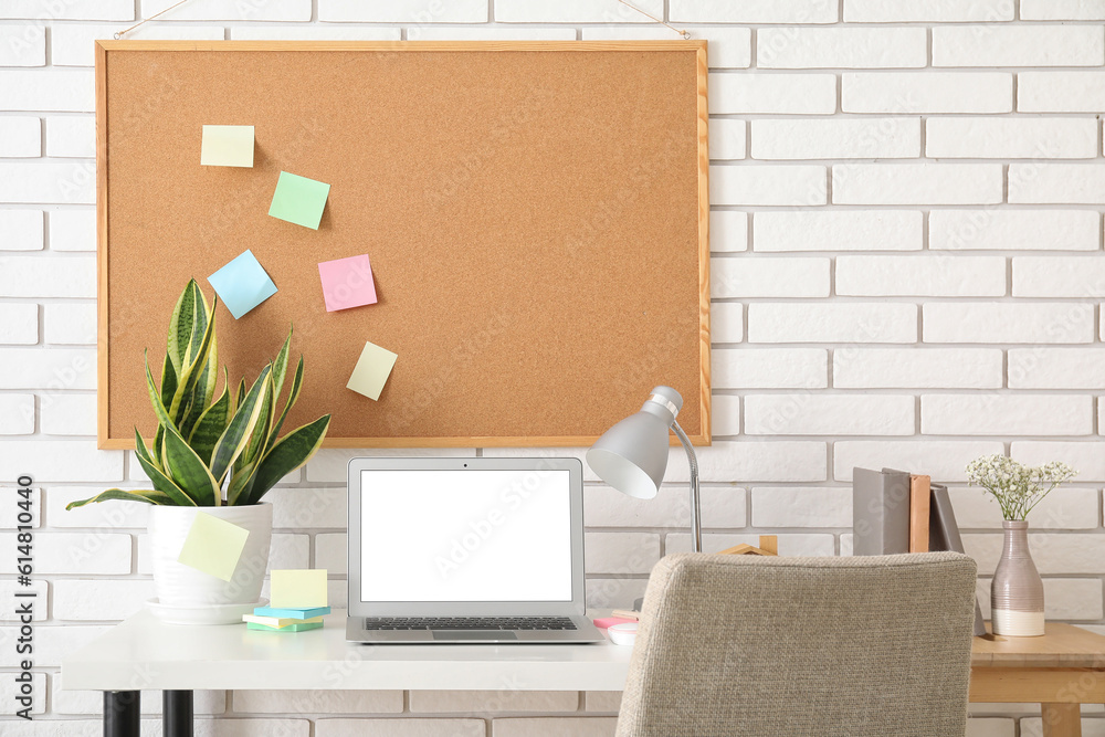 Board with sticky notes and laptop on table in room