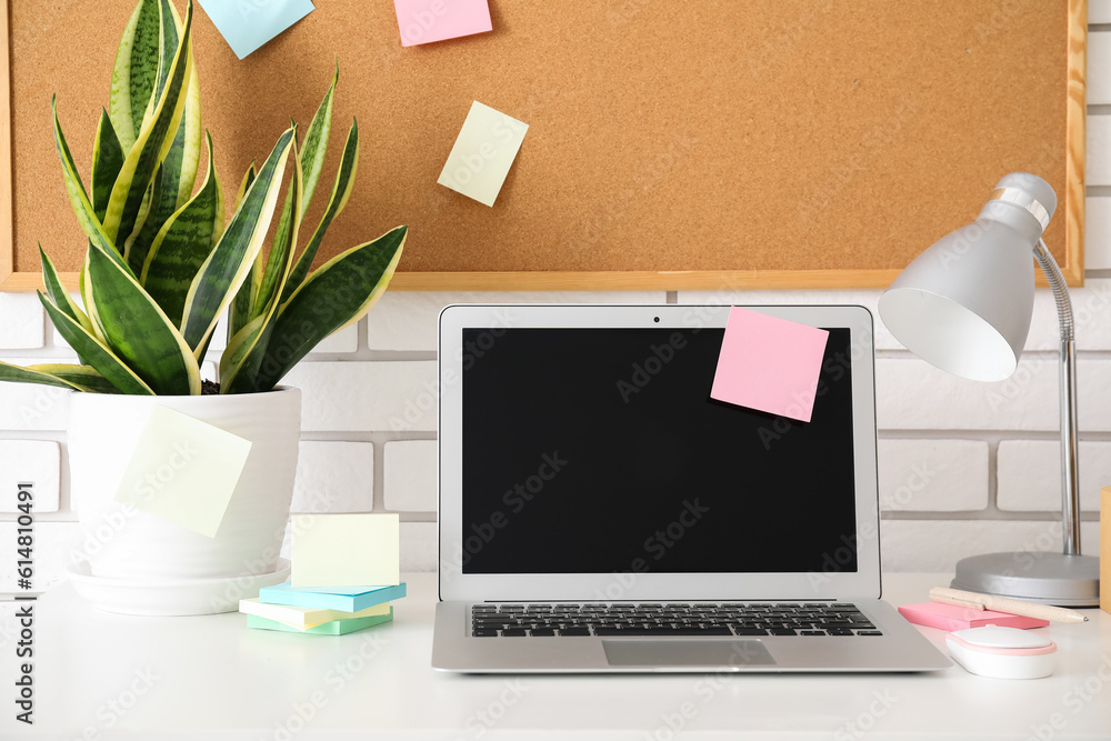 Board with sticky notes and laptop on table in room