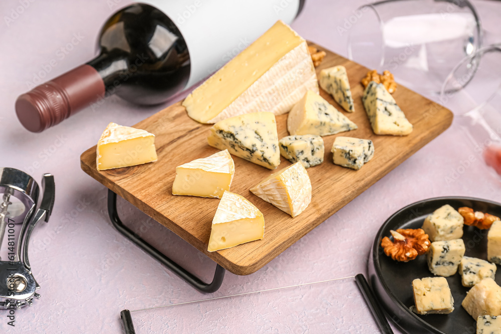 Wooden board with pieces of tasty cheese on light background