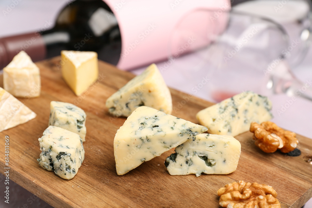 Wooden board with pieces of tasty cheese on table, closeup