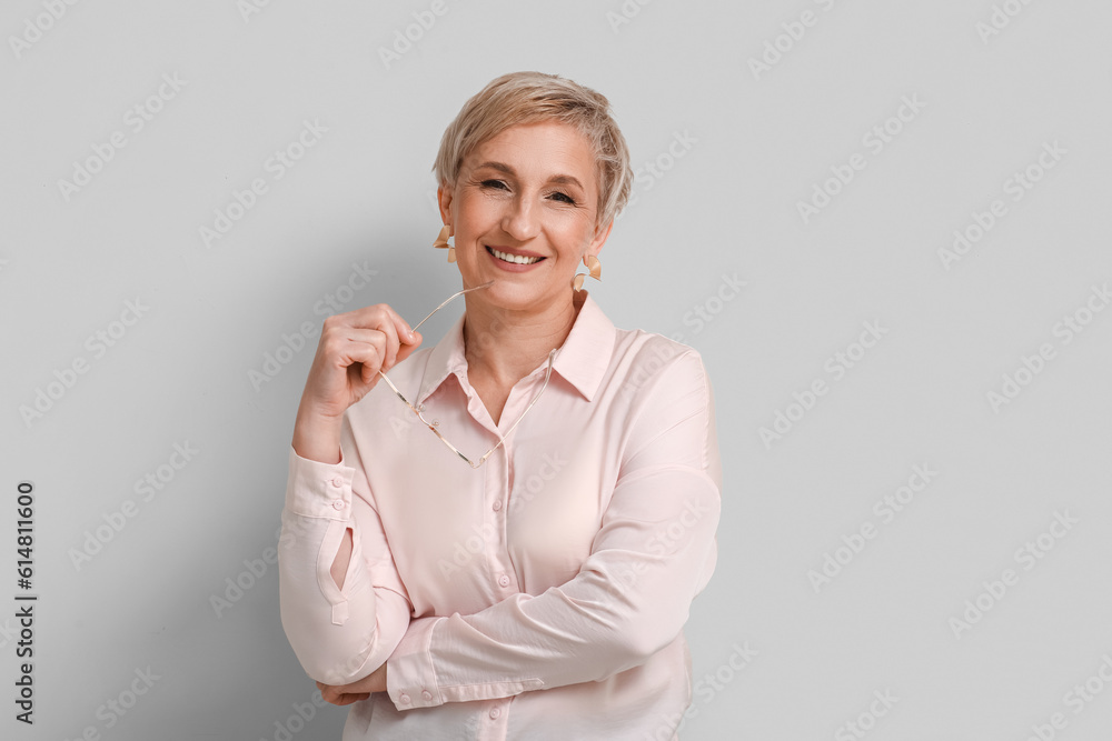 Mature blonde woman with eyeglasses on light background