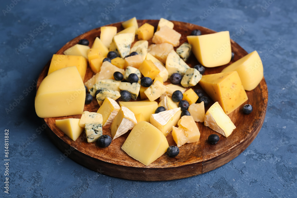 Plate with pieces of tasty cheese on blue background