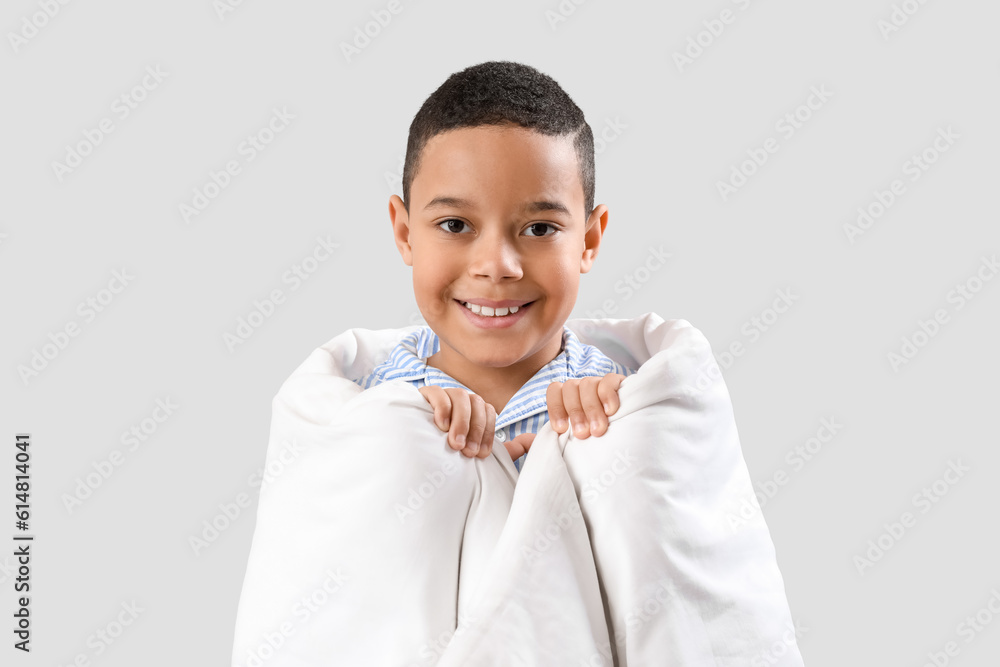 Little African-American boy with soft blanket on light background, closeup