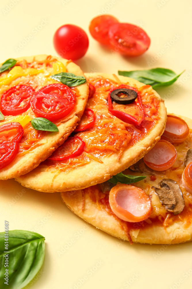 Different tasty mini pizzas on yellow background