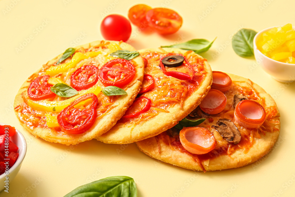 Different tasty mini pizzas on yellow background