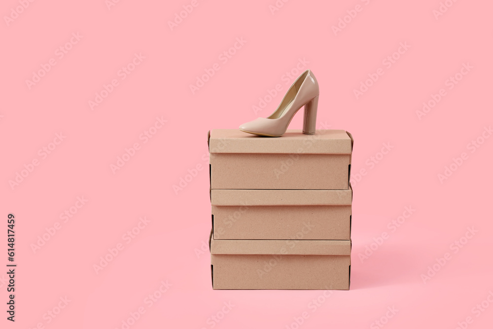 Cardboard boxes with beige high-heeled shoe on pink background