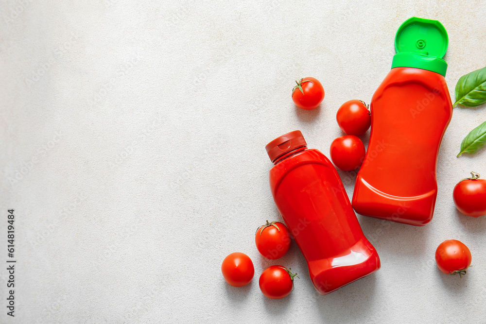 Bottles of ketchup and tomatoes on white background