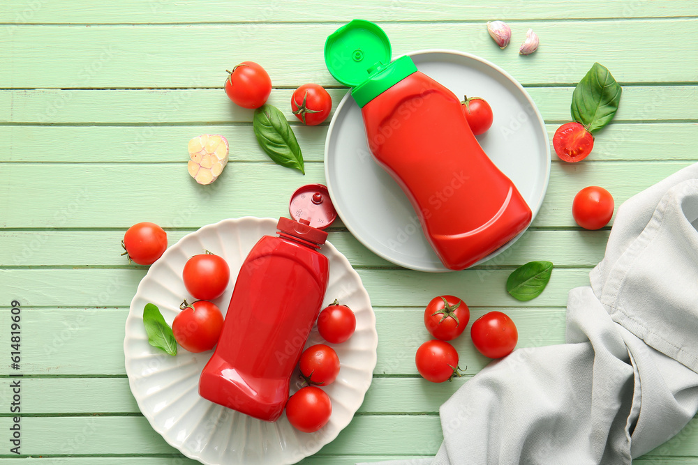 Plates with bottles of ketchup and tomatoes on green wooden background