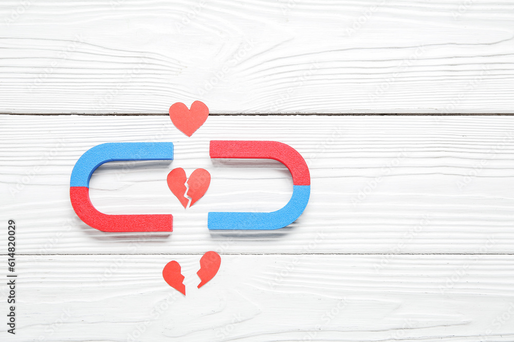 Magnets with paper broken hearts on white wooden background. Divorce concept