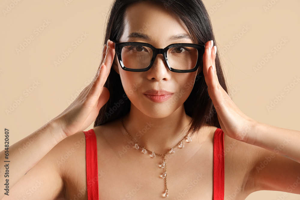 Beautiful Asian woman in stylish eyeglasses on beige background, closeup