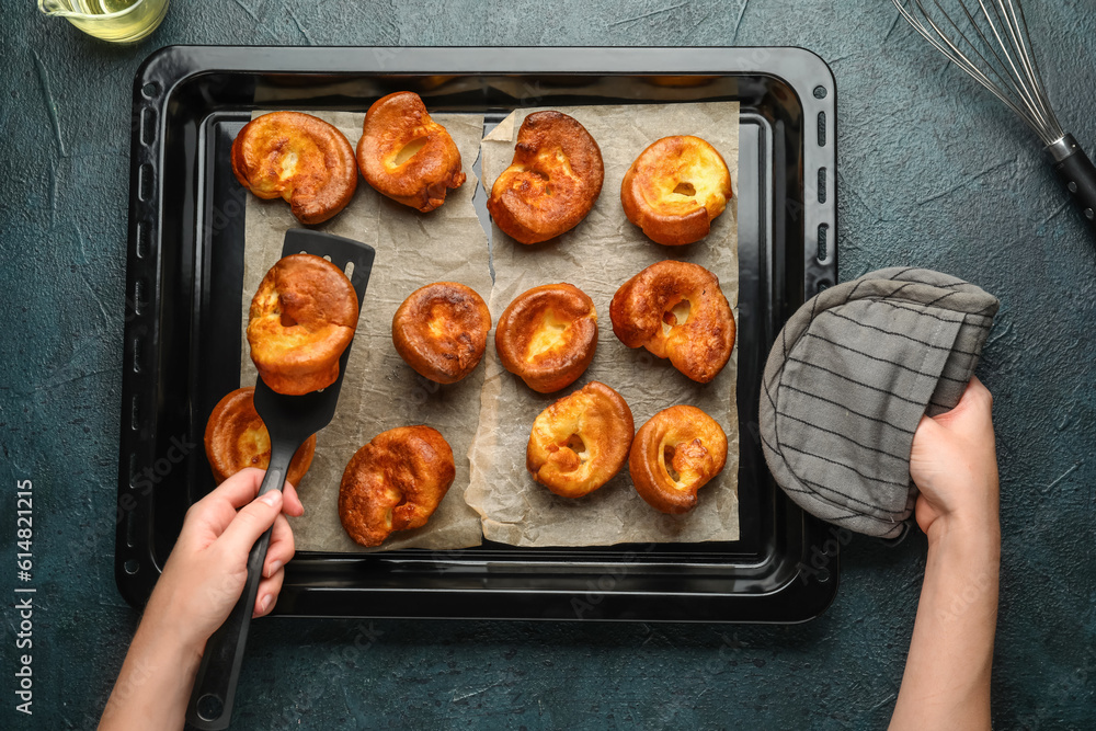 Woman taking tasty Yorkshire pudding from baking tray on blue background