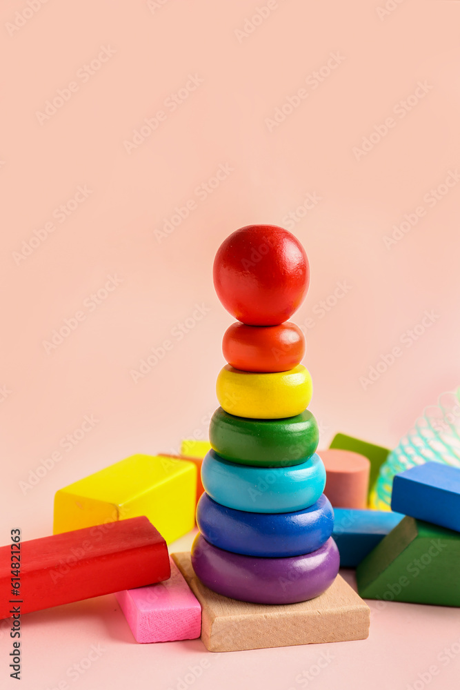 Wooden colorful toy pyramid with rainbow slinky on pink background. Childrens Day celebration