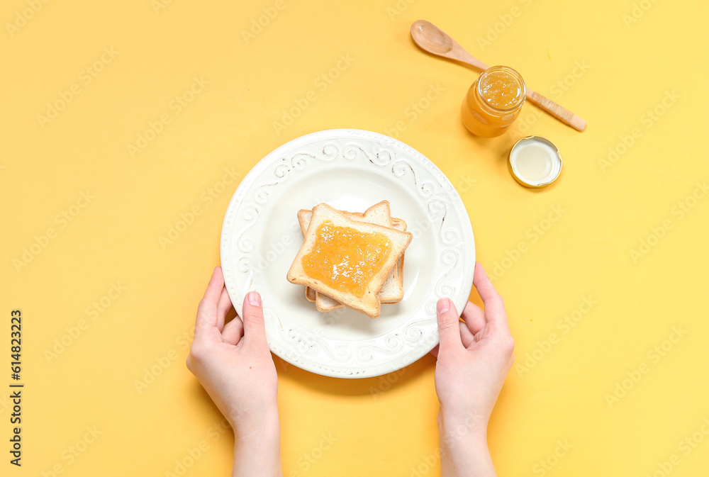 Female hands with plate of tasty toasts and jam on color background