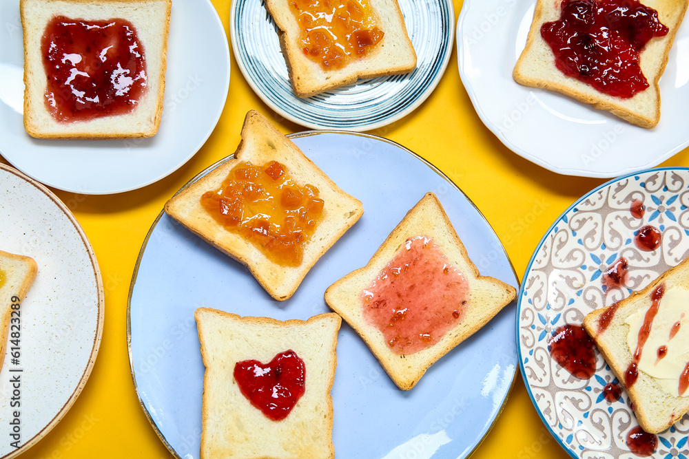 Many plates of delicious toasts with jam on color background, closeup