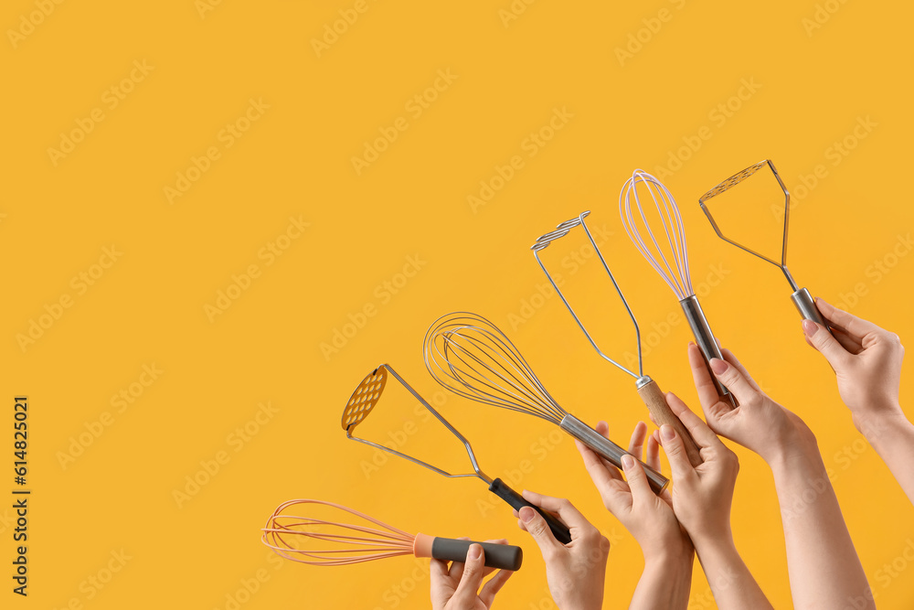 Female hands holding different whisks and mashers on yellow background