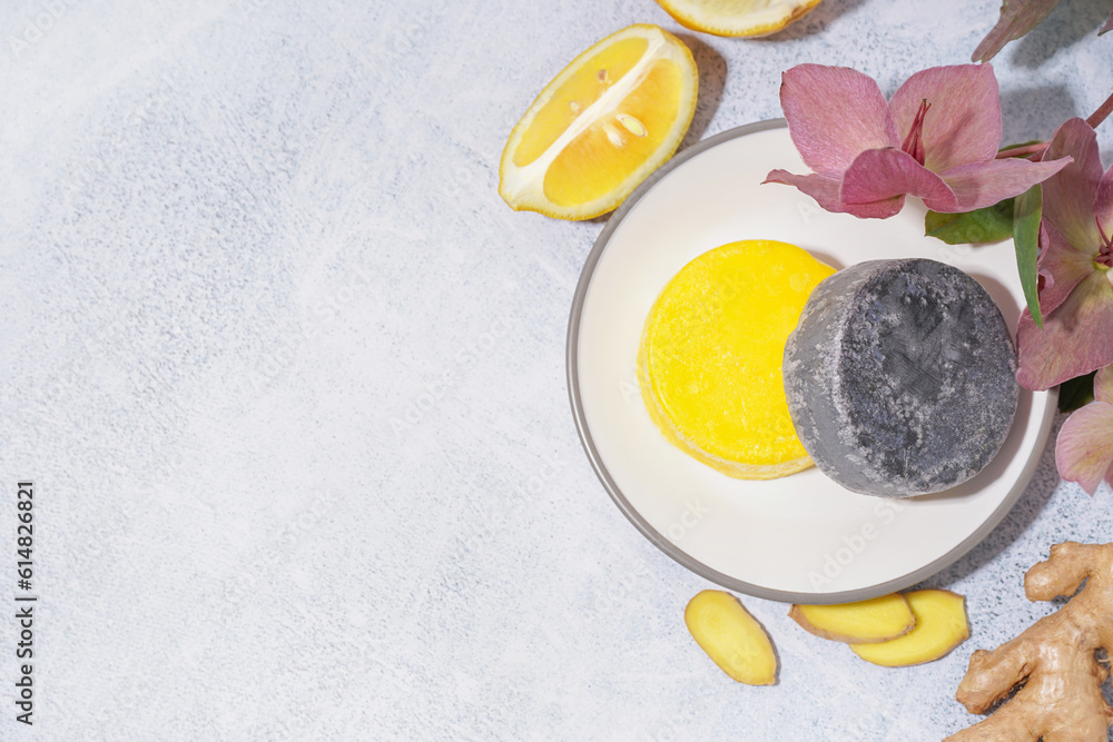 Different handmade solid shampoo, orchid flowers and ginger on light background