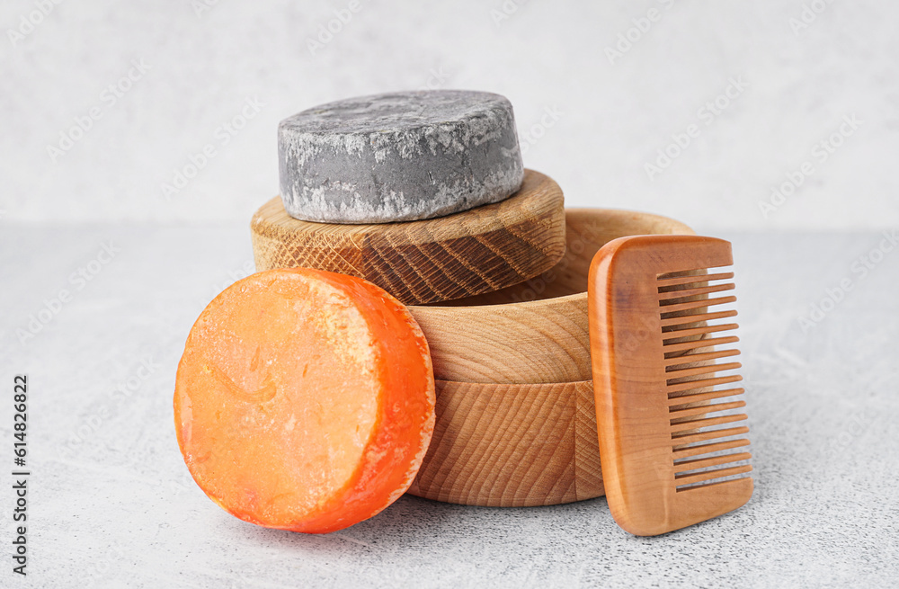 Different handmade solid shampoo and hair comb on light background, closeup