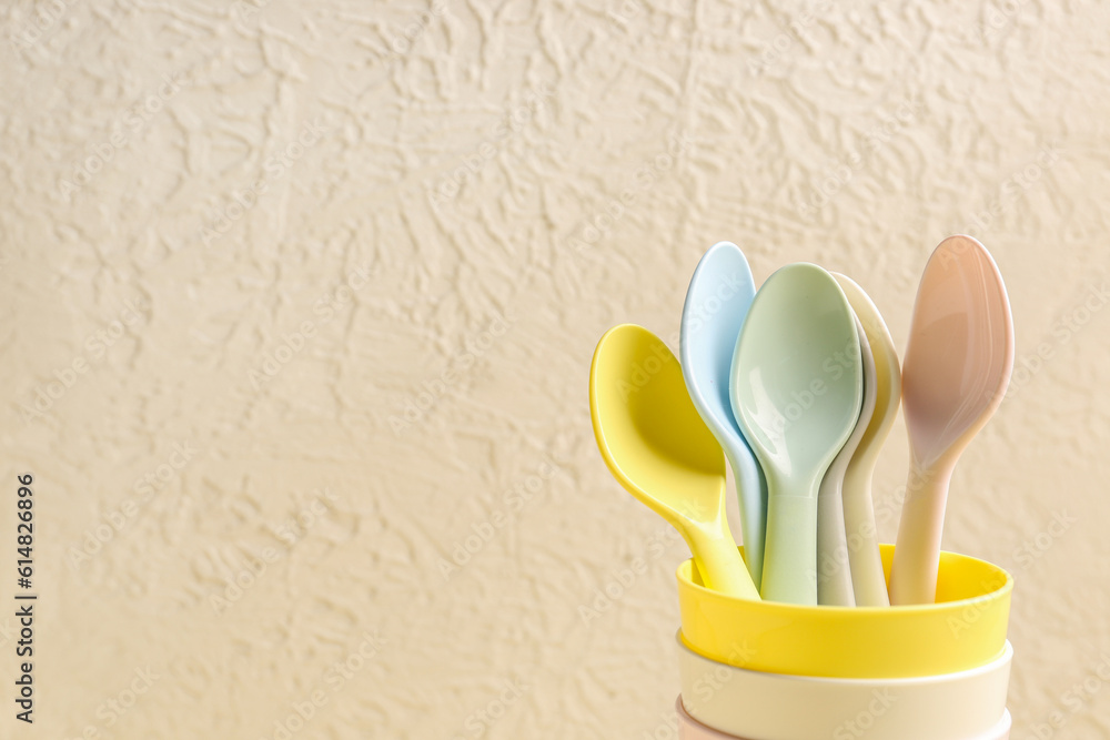 Colorful spoons and cups for baby on white textured background