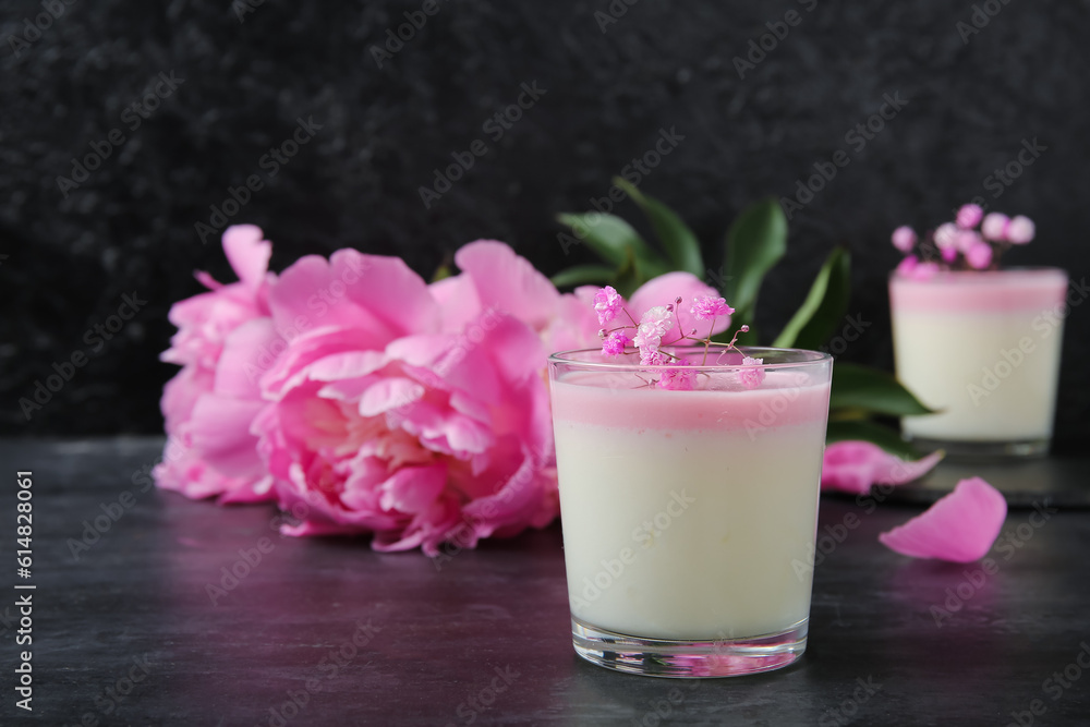 Glasses of panna cotta with beautiful gypsophila and peony flowers on black table