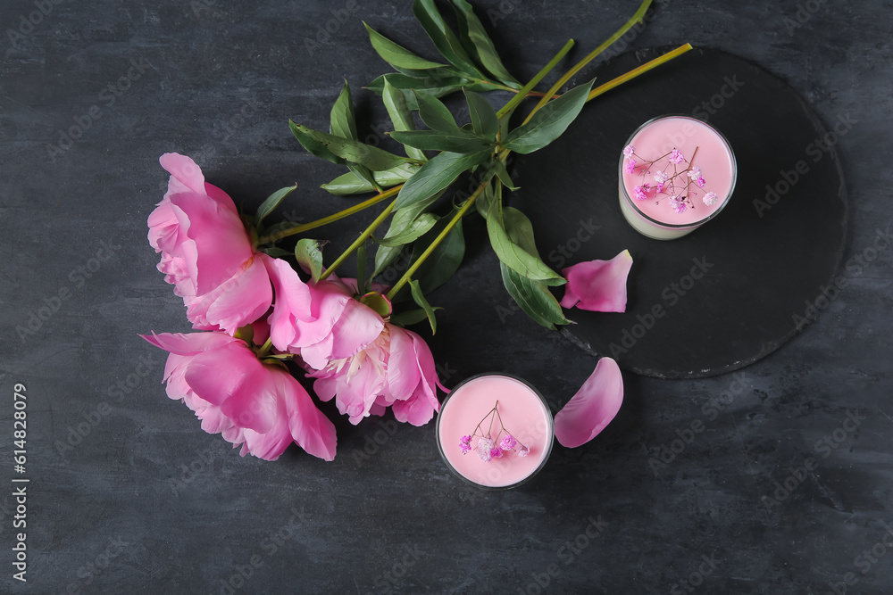 Glasses of panna cotta with beautiful gypsophila and peony flowers on black table