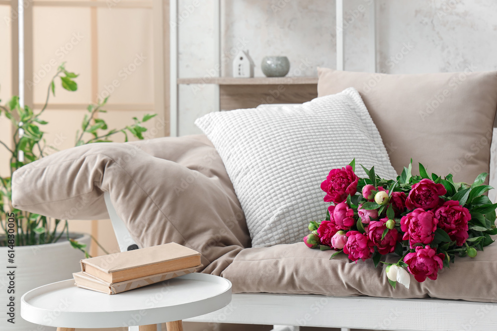 Bouquet of peonies lying on couch in living room