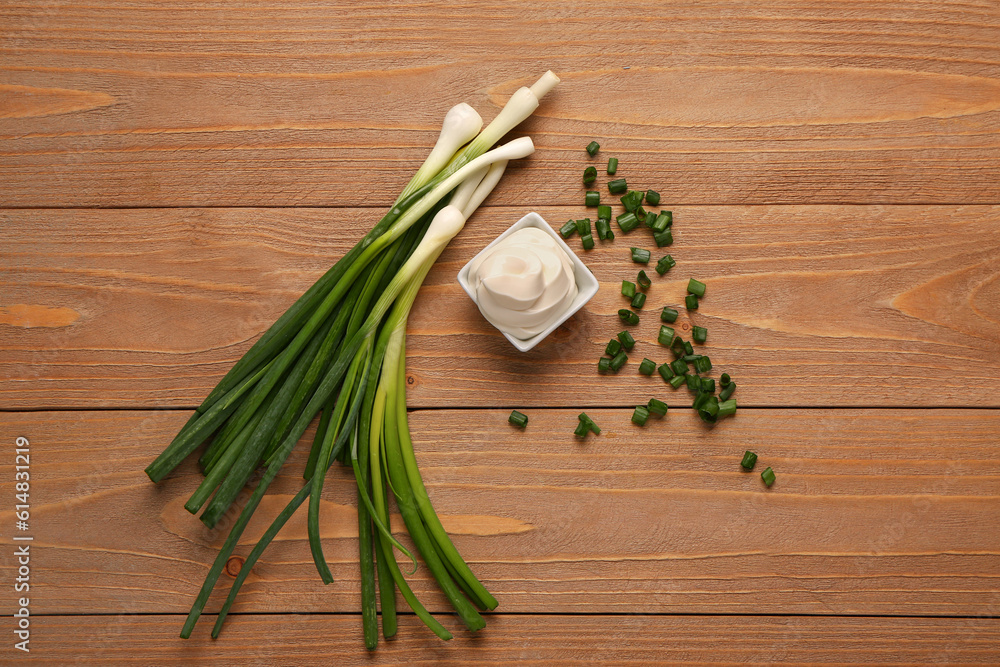 Bowl of tasty sour cream and sliced green onion on wooden background