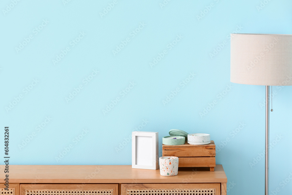 Holders with candles on table and lamp near blue wall in room