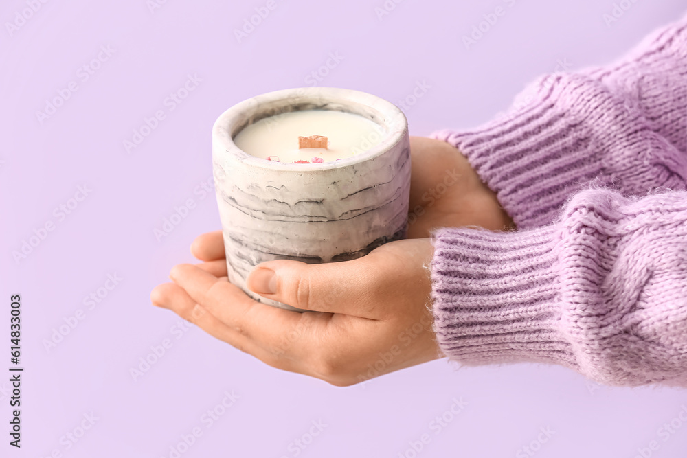 Woman holding candle on purple background, closeup