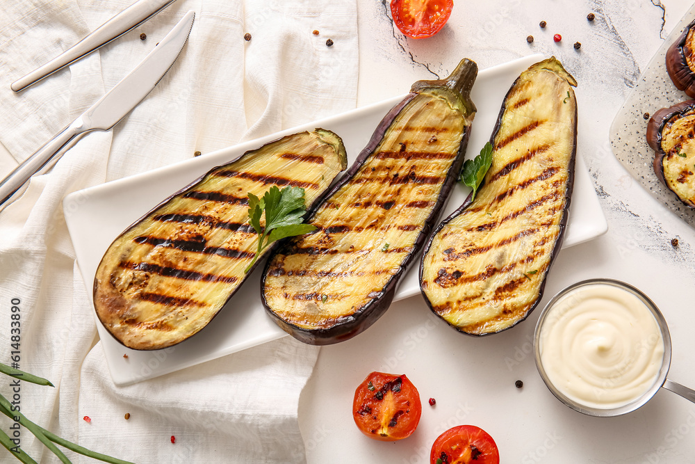 Plate with delicious grilled eggplants, sauce and tomatoes on light background, top view