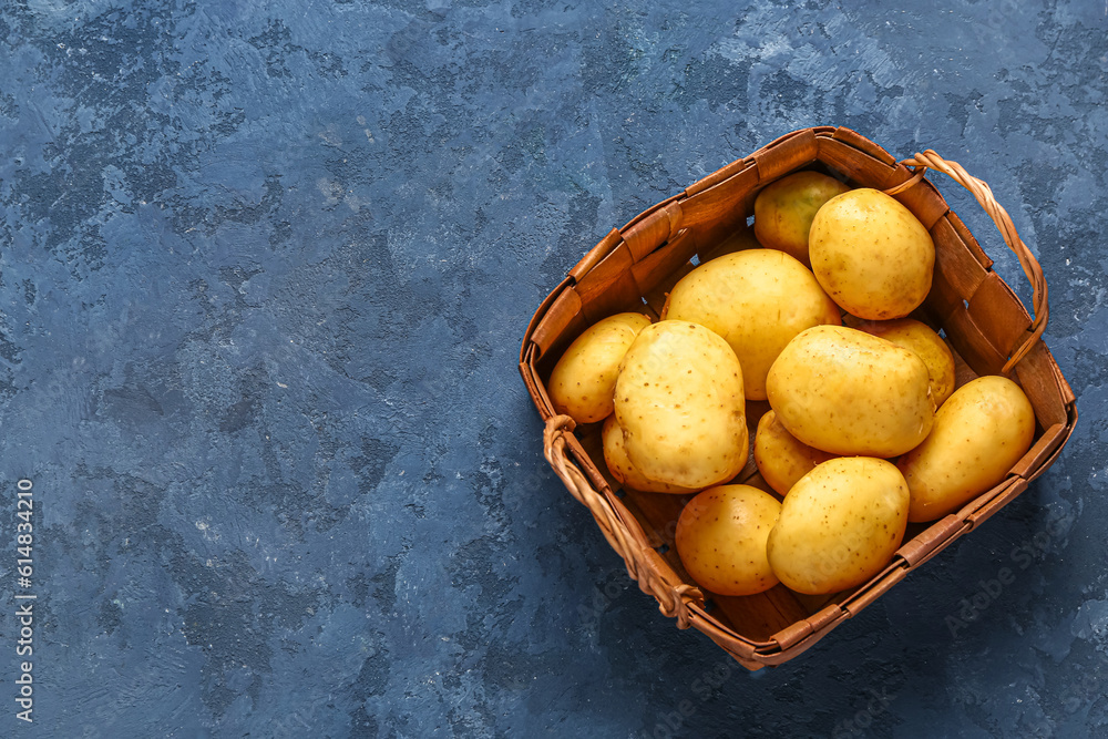 Wicker basket with raw baby potatoes on blue background