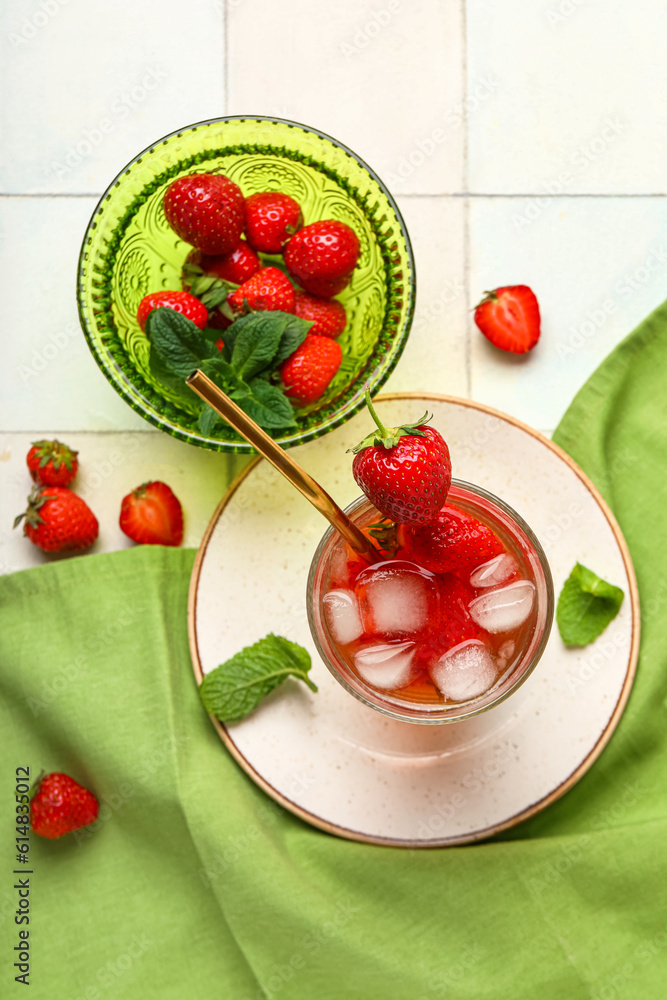 Glass of infused water with strawberry on white tile background