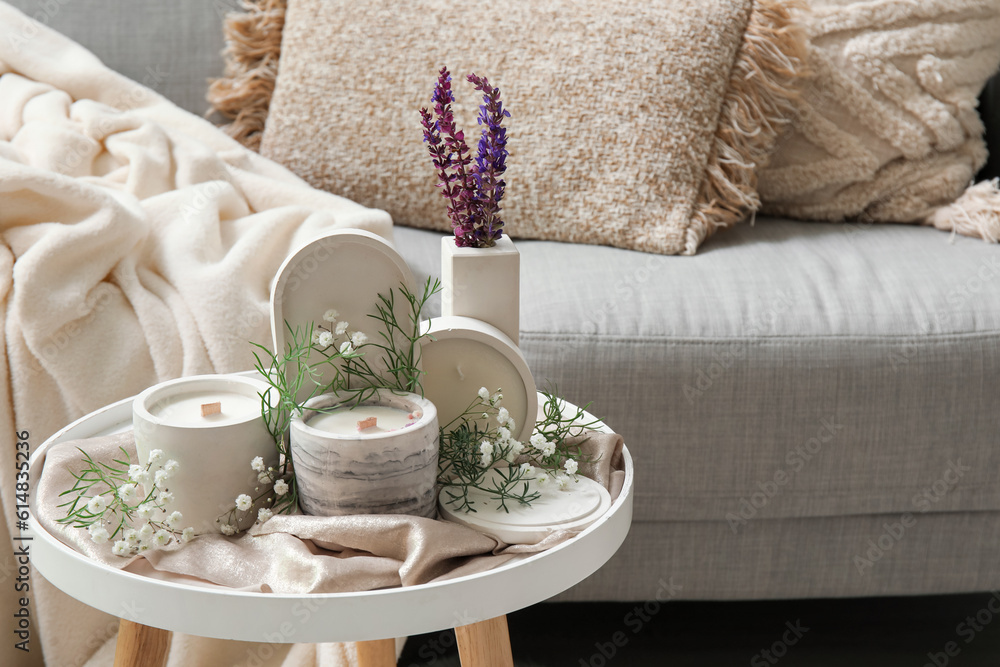 Interior of light living room with sofa, gypsophila flowers and candles on table, closeup