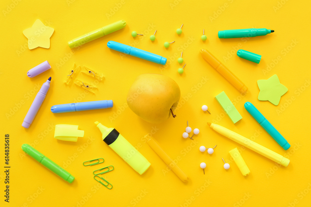 Fresh apple with different stationery on yellow background