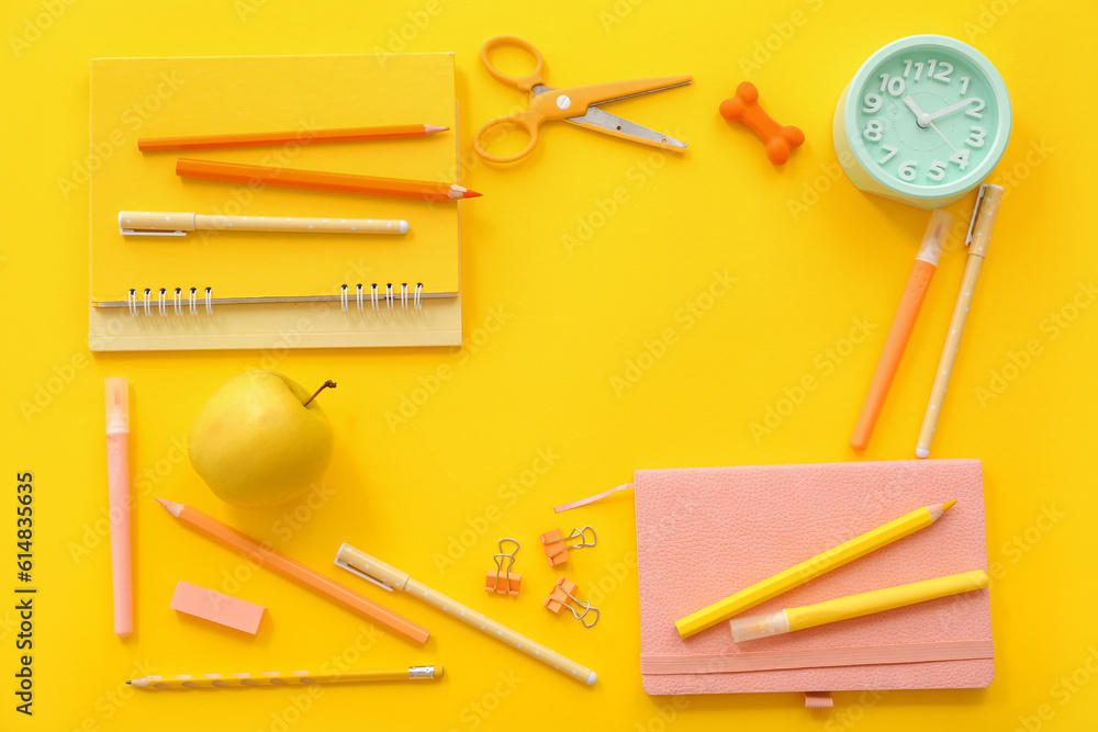 Frame made of alarm clock, fresh apple and different stationery on yellow background