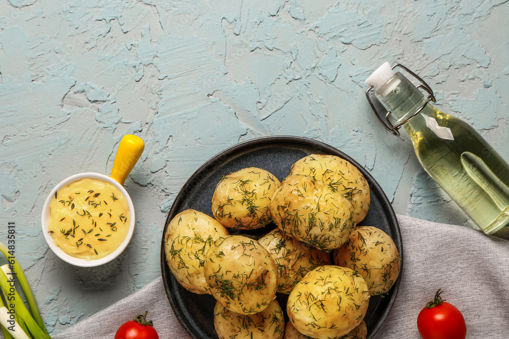 Plate of boiled baby potatoes with dill and sauce on blue background