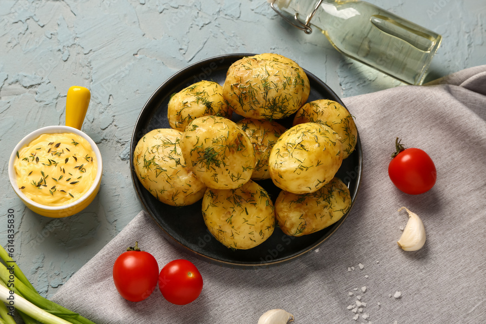 Plate of boiled baby potatoes with dill and sauce on blue background