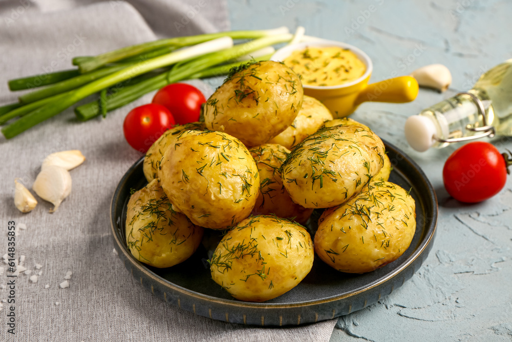 Plate of boiled baby potatoes with dill and sauce on blue background